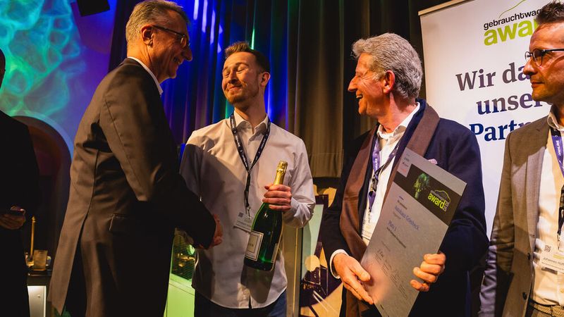 Der Countdown für die Verleihung des Gebrauchtwagen Awards 2025 startet; zunächst für die Kategorie Vertragshandel. Joachim Heim gratuliert den Vertretern des Autohauses Griesbeck zu Platz drei. (Bild: stefan bausewein)