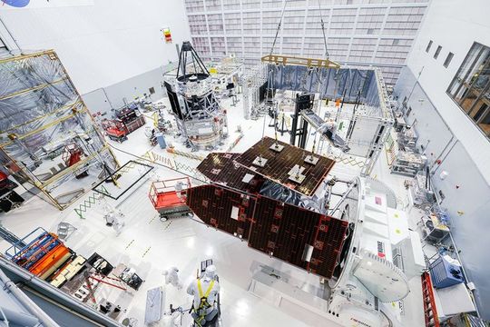 Technicians install solar panels on the outer façade of the observatory. The inner part of the telescope can be seen in the background, slightly to the left of the center of the picture.(Image: NASA/Sydney Rohde)