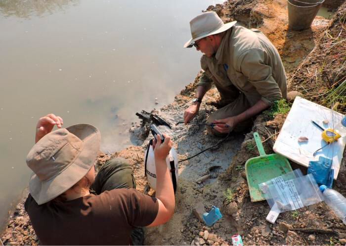 Professor Larry Barham (pictured, right) uncovering the wooden structure on the banks of the river with a fine spray (Source: Professor Geoff Duller, Aberystwyth University)