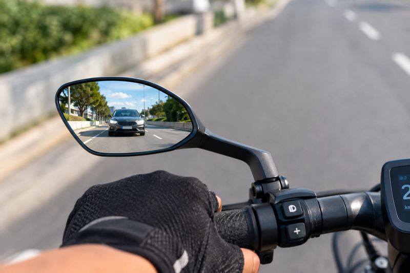 Den Verkehr entspannt im Blick: Ein fest montierter, wackelfreier Rückspiegel erleichtert die Orientierung nach hinten enorm. Wichtig: Den rettenden Schulterblick vor dem Abbiegen ersetzt er jedoch nicht. (Bild: KI-generiert / Dall-E)