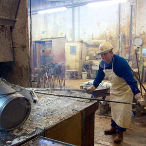 Auf der einen Seite des Beckens steht ein Mann mit einer bodenlangen Gummischürze. In den Händen hat er eine über 2 m lange Spezialzange, mit der er einen Blecheimer in eine gräuliche Flüssigkeit taucht, tief ins Becken drückt und weit nach vorne schiebt.
