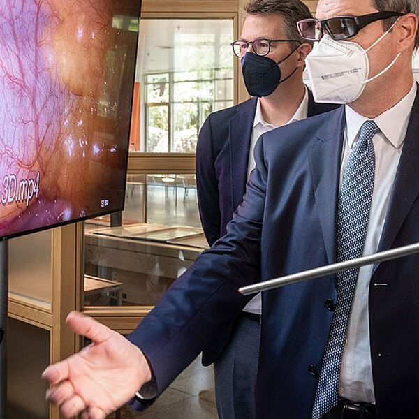 Wissenschaftsminister Markus Blume und Ministerpräsident Markus Söder betrachten am Deutschen Herzzentrum München eine 3D-Darstellung von Blutgefäßen.