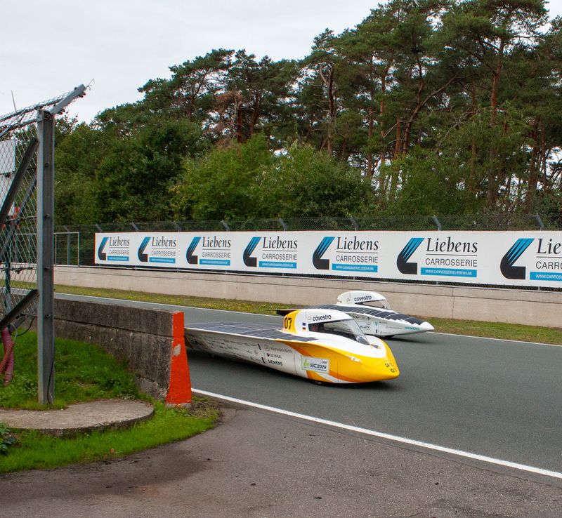 The Æthon solar cars in the foreground and the Adelie in the background on the racetrack in Zolder.(Source:  Team Sonnenwagen)
