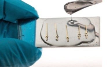 Vernis photopolymérisable pour la fixation temporaire / ou vernis d’épargne soluble dans un éco-solvant. Ici : fixation temporaire d’aiguilles d’une montre  en vue de diamatage et polissage de la surface. (Image: Horlovia Chemicals)