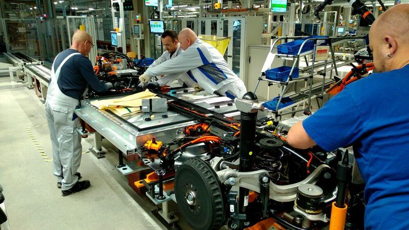 Die Hinterachse wird montagefertig angeliefert und automatisiert ins Fahrgestell eingebaut. Einige manuelle Handgriffe sind aber weiterhin notwendig, zum Beispiel um Kabel und die Verschlauchung des Kühlsystems des Akkus zu montieren. (Thomas Günnel/Automobil Industrie)