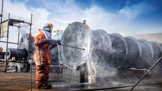 Ein Arbeiter reinigt einen Wärmetauscher: Nicht nur deren Verkalkung an sich kostet viel, sondern auch, dass die gesamte Anlage für Reinigung außer Betrieb gesetzt werden muss.  (Bild: adel - stock.adobe.com)