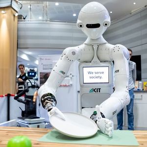Der Roboter ARMAR-7 des Karlsruher Institut für Technologie (KIT) greift vorsichtig einen Teller, um ihn den Geschirrspüler einzuräumen. Er ist insbesondere mit einer kognitiven Architektur mit einem episodischem Gedächtnis ausgestattet, um seine Erfahrungen zu speichern, abzurufen und zu teilen. (Bild:  DLR (CC BY-NC-ND 3.0))