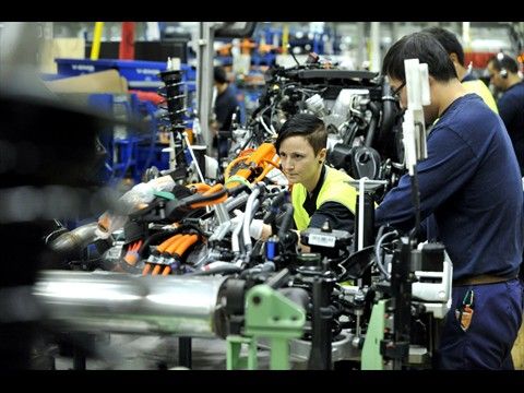 Produktion des Volvo V60 Plug-in-Hybrid auf einem Band mit anderen Modellen: Hybrid-Spezialistin Sofia Nordgren verlegt das orangefarbene Hochspannungskabel zwischen Batterie und Motorraum. (Bild: Volvo)