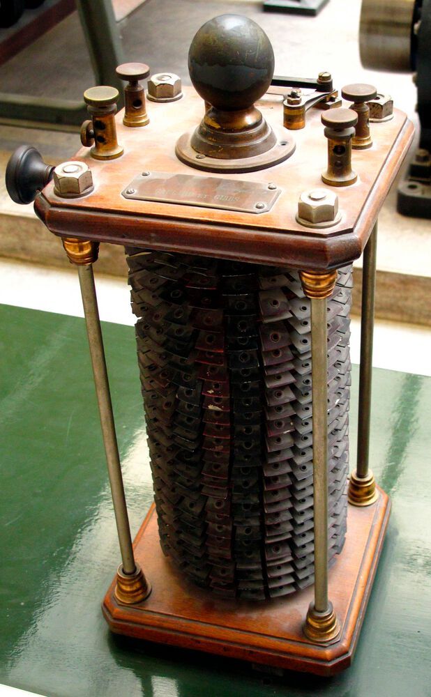 Im Bild: Frühe Verteilnetz-Transformatoren von Gaulard und Gibbs. Mehrere dieser Transformatoren wurden 1884 auf der Turiner Elektrizitätsaustellung vorgeführt um von einer Wasserkraftanlage in Lanzo eine Leistung von 20 kW mit einer Spannung von 2000 V über 40 km nach Turin zu übertragen. 