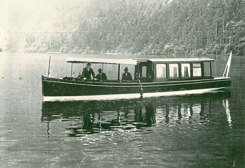 1909 – Elektromotorboot „Accumulator“: Mit Zustimmung des Prinzregenten Luitpold bestellte der Obersthofmeisterstab im Jahr 1909 vier Boote – ein Elektroboot, zwei mit Petroleum befeuerte Dampfmaschinenboote und ausschließlich für Hofdienstzwecke ein kleines Elektroboot. Ihren Anfang nahm die Motorschifffahrt schließlich am 15. Juli 1909 mit dem von Siemens-Schuckert gelieferten Elektromotorboot „Accumulator“ (1910 auf „St. Bartholomä“ umgetauft). Es fasste 38 Personen, war 12 m lang, 2,15 m breit und hatte etwa 15 PS. Bootskörper und Kajüte waren aus Mahagoni. Die erforderliche Energie lieferte eine Bleibatterie, die bei einer Geschwindigkeit von 10 km/h einen Aktionsradius von rund 100 Kilometern ermöglichte. Kurz nach der Indienststellung der „Accumulator“ wurden die beiden 18 Personen fassenden Dampfmaschinenboote „Tristan“ und „Isolde“ gewassert. Das für hofdienstliche Zwecke hochherrschaftlich ausgestattete Elektromotorboot „Gemse“ kam wenig später hinzu und konnte bis zu 20 Personen transportieren.  (Bild: Bayerische Seenschifffahrt)