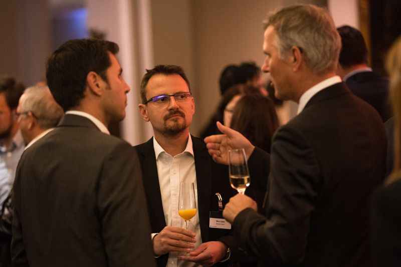 Von links nach rechts: Markus Späth und Nico Litzel (beide Vogel IT-Medien) im Gespräch mit Alfred Vöhringer von T-Systerms beim Sektempfang in der Lobby. (artful rooms / Vogel IT-Medien GmbH)