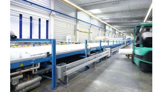 Auf mehren 100 m langen Produktionslinien werden CFK-Bahnen mit Oberflächenversiegelung für Fahrzeugaufbauten hergestellt.  (Bild: Lamilux)