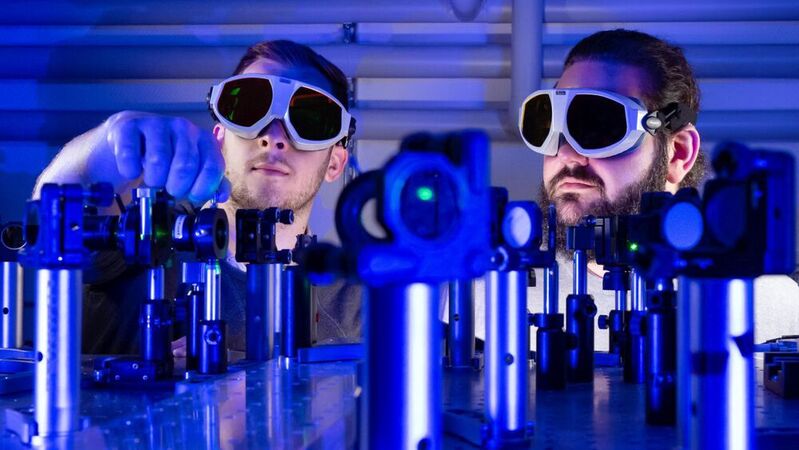 Die Doktoranden Paul Herrmann (l.) und Sebastian Klimmer experimentieren mit monokristallinen 2D-Materialien und Laserlicht. Sie haben die bekannte physikalische Methode der Frequenzverdopplung von Licht mit einer besonderen Materialeigenschaft, der Valleypolarisation, kombiniert und dabei erstaunliche Ergebnisse erzielt. 