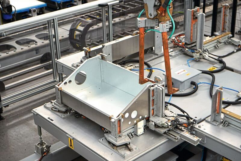 Vom Handlingroboter auf den Drehtisch positioniert, wird das Blechgehäuse mittels robotergeführter Schweißzange punktgeschweisst. (Salvagnini)