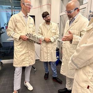 Sebastian Härtner (MTP-Experte bei Merck, links) zeigt dem hessischen Staatsekretär Daniel Köfer (rechts) und dem Landtagsabgeordneten Bijan Kaffenberger (Mitte) ein Reaktionsmodul bei einem Besuch im August 2026. (Bild: Merck)