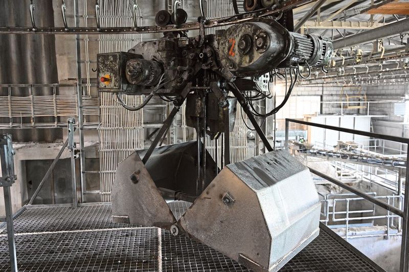 Entlang eines Schienensystems laufen Greifer, die nach und nach die Rohstoffkeller anfahren, bis das richtige Mischungsverhältnis des Pegmatitsands erreicht ist.   (Bild: Shamika Löchel, BAM GmbH)