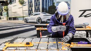Schutzhelm mit Visier, spannungssicherer Overall und dicke Hochvolt-Handschuhe: Mit der angelegten Schutzausrüstung wird selbst einfache 
Schraubarbeit bei der Batteriereparatur zur 
Herausforderung. (Bild: Porsche)