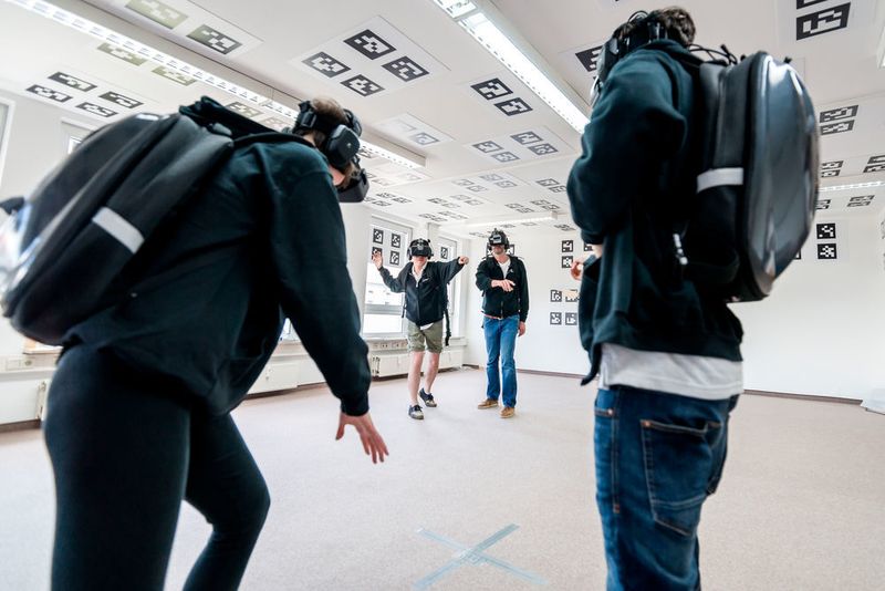 Illusion Walk (www.illusion-walk.com) wurde 2013 gegründet. Das Start-up aus Berlin arbeitet an einer begehbaren VR-Plattform, auf der Nutzer mit Freunden in virtuellen Welten spazieren gehen können. Sie nehmen die Umwelt durch eine VR-Brille wahr, während sie sich durch die Räume bewegen. In Zusammenarbeit mit der TU Wien hat Illusion Walk nun auch die Möglichkeit geschaffen, dass sich mehrere Nutzer gleichzeitig in der VR-Welt bewegen können. (Illusion Walk)