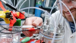 Kevinjeorjios Pellumbi mit dem Versuchsaufbau für die CO2-Umwandlung (Bild: RUB, Marquard)