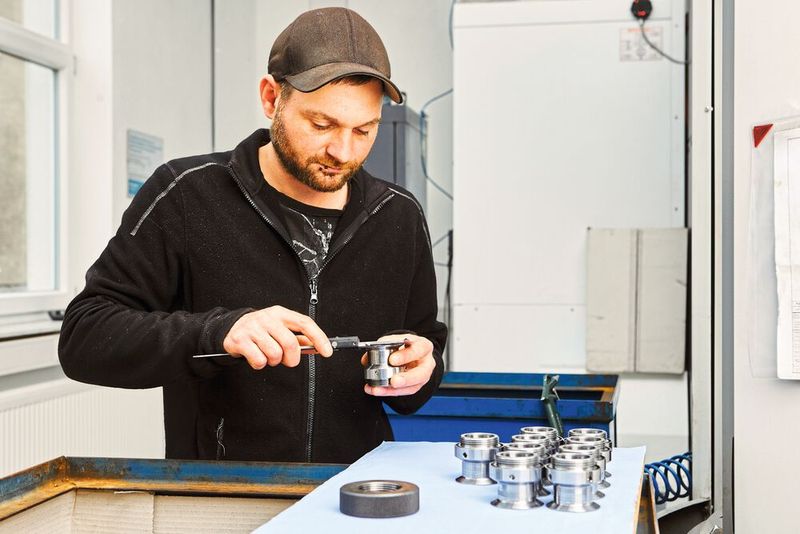 Christopher Krause prüft die bearbeiteten Fertigteile, hier Einschraubstutzen für den Kompressorenbau.  (Bild: Schunk)