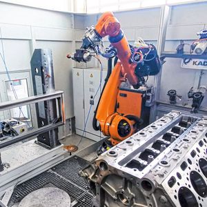 Sinnbild für die Mobilitätstransformation: In der Versuchszelle bei Kadia steht vorne noch ein Schiffsmotorblock, während hinten Tests für die Bearbeitung einer Batteriewanne für Elektrofahrzeuge durchgeführt werden. Die jeweils notwendigen Einheiten greift sich der Roboter aus dem Magazin.(Bild:  Kadia Produktion GmbH + Co.)