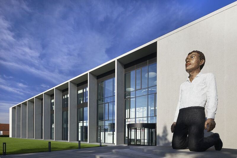 „Großer Kniender“: Die 5,7-m-Außenskulptur des Bildhauers Stephan Balkenhol steht vor dem Eingang des neuen Schulungs- und Ausstellungszentrums von Hörmann. (Bild: Hörmann)