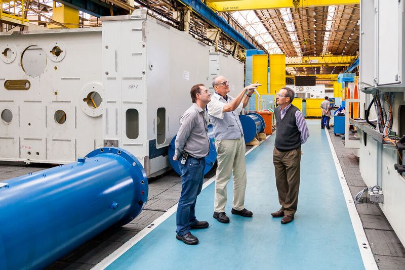 Werksleiter Ivo Savietto Neto (rechts) und Mitarbeiter Fabio Avila zeigen dem Reporter Nikolaus Fecht die Endmontage von Pressen-Kopfstücken. (Prensas Schuler/Koiti Photos 2019)