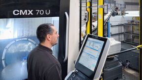 Mr Slimm at the control of the automated DMG Mori CMX 70 U VMC. The robot enclosure with safety fence and light curtain may be seen in the background. (Source: Whitehouse Machine Tools )