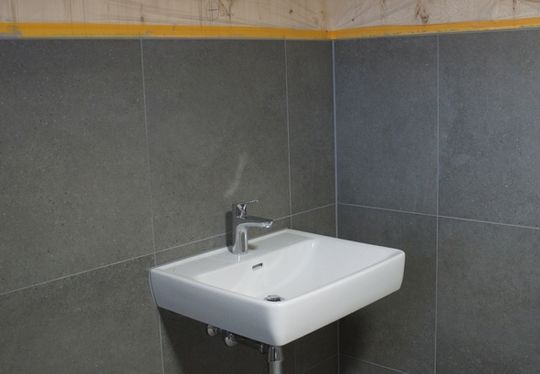 (In den Sanitärräumen kam eine großformatige Fliese in einem Grauton für Wand und Boden zum Einsatz. Foto: Botament)