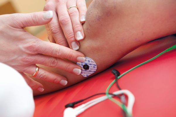 Eine Therapeutin befestigt Sensoren auf der Haut der Patientin. Diese werden anschließend mit dem Roboteranzug verkabelt. (Marion Nelle)