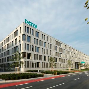 Datev IT-Campus: Hinter der Muschelkalkfassade mit den unregelmäßigen Fenstern arbeiten rund 1.800 Mitarbeiterinnen und Mitarbeiter aus der Software-Entwicklung. Über dem Eingangsbereich schwebt ein „DATEV“-Logo mit aufgestelltem Schriftzug. Die Anlage wurde im Rahmen eines studentischen Wettbewerbs von drei Design-Studentinnen der Hochschule Hof entwickelt.(Bild:  Kurt Fuchs/ DATEV eG)