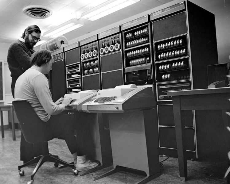 Ken Thompson (sitzend) und Dennis Ritchie an einem Rechner PDP-11, den ihnen Bell Labs 1970 zum Programmieren eines Textverarbeitungsprogramms zur Verfügung stellte. (Peter Hamer / CC BY-SA 2.0)