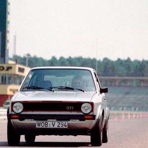 Am 1. Juni 1976 erfolgt der Serienanlauf des GTI, vorerst nur als Dreitürer und in den Farben Marsrot oder Diamantsilber. Er verfügt über den 110 PS (81 kW) starken Motor des Audi 80 GTE, hat innenbelüftete Scheibenbremsen vorn und einen zusätzlichen Ölkühler. An der Vorderachse sitzt ein Stabilisator und an der Hinterachse ein lastabhängiger Bremskraftregler. Das Sportlenkrad war mit drei gelochten Speichen versehen – der tiefe Pralltopf mit der Hupenbetätigung erhielt rasch den Spitznamen „Spucknapf“. Der Schaltknauf war als Golfball ausgeführt. Kotflügel-Verbreiterungen aus Kunststoff, ein größerer Frontspoiler, Reifen der Größe 175/70 HR 13 auf Felgen 5,5Jx13, ein rot-gerahmter Kühlergrill und die mit schwarzer Klebefolie eingefasste Heckscheibe waren weitere Kennzeichen des damals stärksten Golf-Modells. (Bild:  Volkswagen AG)