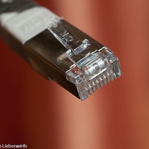 Abbildung 1: RJ 45 Stecker. Netzwerkkabel, die für einen Switch geeignet sind,  haben verdrillte Adernpaare (twisted pair) für einen besseren Schutz gegen elektromagnetische Felder. Crosskabel hingegen sehen ähnlich aus, funktionieren jedoch nur, um Computer direkt untereinander zu verbinden.