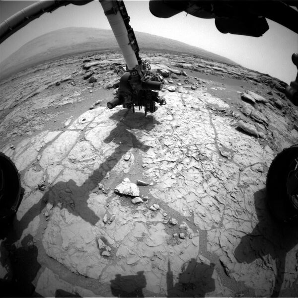 28. Januar 2013: Der Schlagbohrer im Werkzeugturm am Ende des Roboterarms des NASA-Marsrovers Curiosity hat auf diesem Bild der vorderen Hazcam (Hazard-Avoidance Camera) des Rovers Kontakt mit der Felsoberfläche. Der Bohrer wurde für Vorbelastungstests positioniert, und die Hazcam nahm dieses Bild während des 170. Marstages oder Sols von Curiositys Arbeit auf dem Mars (27. Januar 2013) auf. Vor der ersten Bohrung in ein Gestein auf dem Mars, bei der eine Gesteinsprobe zur Analyse entnommen wird, sind weitere Tests mit dem Bohrer geplant. In dieser Ansicht wird der Bohrer auf ein Ziel in einem flachen, geäderten Felsstück namens 