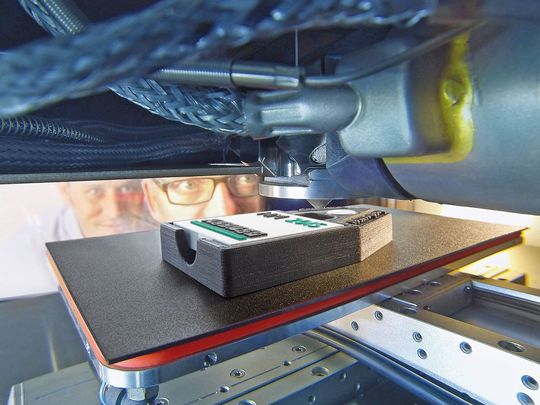 Bei der additiven Fertigung mittels AKF-Verfahren bewegt sich der Bauteilträger über drei Achsen auf wenige Mikrometer genau unter der starren Austragseinheit. Bei der additiven Fertigung mittels AKF-Verfahren bewegt sich der Bauteilträger über drei Achsen auf wenige Mikrometer genau unter der starren Austragseinheit.