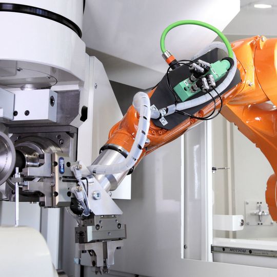 Der Roboter entnimmt mit einem Doppelgreifer das bearbeitete Werkstück und bringt anschließend das neue Werkstück ein. Der Roboter entnimmt mit einem Doppelgreifer das bearbeitete Werkstück und bringt anschließend das neue Werkstück ein.