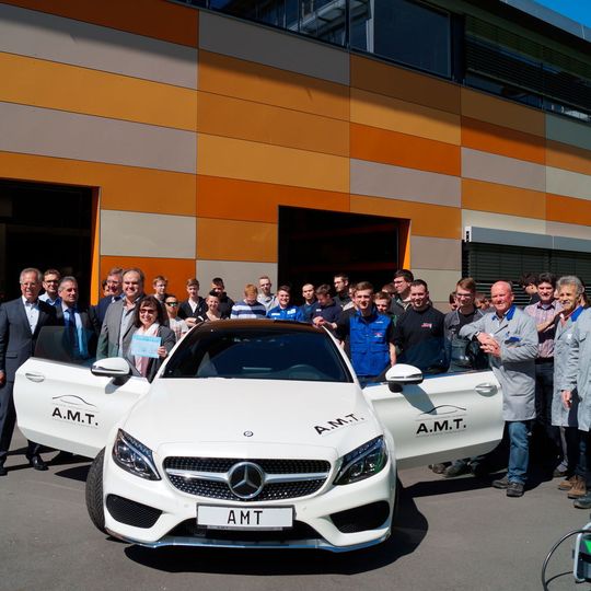 Auszubildende und Fachlehrer freuen sich über das neue Auto.