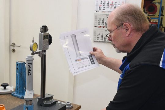 Mit Granitplatte und Höhenmesser kontrolliert Michael Eckert eine Karosserieaufnahme für einen Touran anhand eines selbst erstellten Maßblattes.