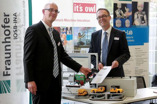 Thomas Eisenbach (RTB GmbH & Co. KG, links) demonstriert Günter Korder (Geschäftsführer it's OWL Clustermangement GmbH) das neue Assistenzsystem für die Montage von Verkehrsgeräten, bei dem der Werker über einen Barcodescanner geführt wird. Thomas Eisenbach (RTB GmbH & Co. KG, links) demonstriert Günter Korder (Geschäftsführer it's OWL Clustermangement GmbH) das neue Assistenzsystem für die Montage von Verkehrsgeräten, bei dem der Werker über einen Barcodescanner geführt wird.
