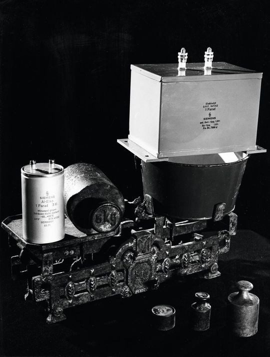 Riesenkondensator: Auf beiden Waagschalen liegen Kondensatoren mit der Kapazität von 1 F. Die rechte Ausführung, 1939 von Siemens gebaut, galt als Höchstleistung des Kondensatorbaus. Die linke wurde zur Hannover Messe 1971 gezeigt. Riesenkondensator: Auf beiden Waagschalen liegen Kondensatoren mit der Kapazität von 1 F. Die rechte Ausführung, 1939 von Siemens gebaut, galt als Höchstleistung des Kondensatorbaus. Die linke wurde zur Hannover Messe 1971 gezeigt.