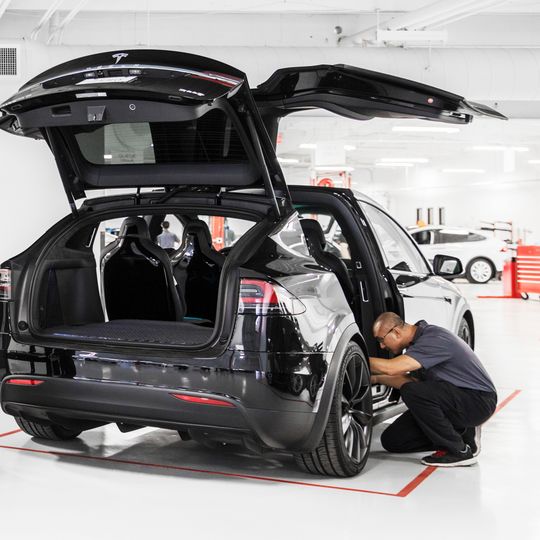 Ein Mitarbeiter eines Tesla-Centers an einem Model X.
