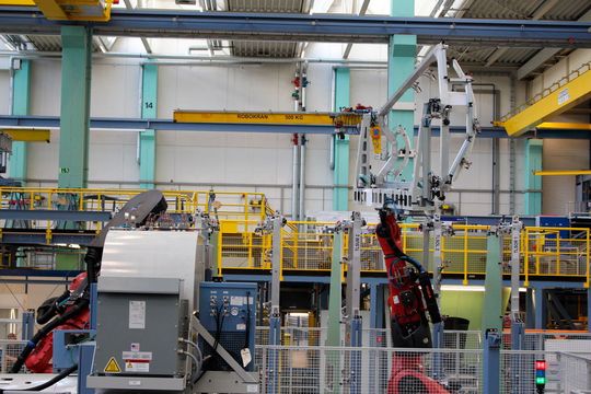 Ein Handlingroboter auf einer Linearachse führt den leeren Bauträger der Beladestation zu, damit er mit einer Schale bestückt werden kann. Ein Handlingroboter auf einer Linearachse führt den leeren Bauträger der Beladestation zu, damit er mit einer Schale bestückt werden kann.