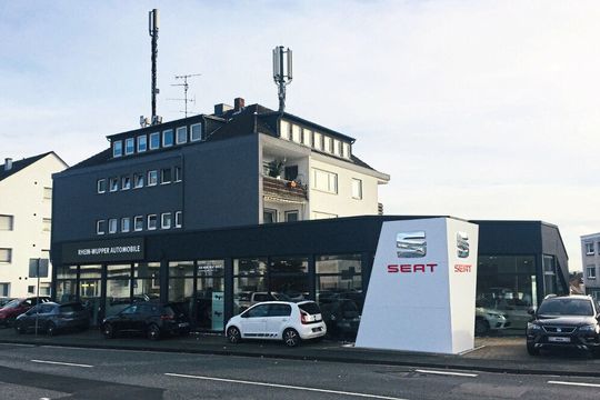 Das Seat-Autohaus an der Lützenkirchener Straße in Leverkusen liegt im Erdgeschoss eines Mehrfamilienhauses. Auffällig ist der „Corner Wall“, ein abgeschrägtes Eckelement mit silbernem Seat-Logo und rotem Schriftzug. Das Seat-Autohaus an der Lützenkirchener Straße in Leverkusen liegt im Erdgeschoss eines Mehrfamilienhauses. Auffällig ist der „Corner Wall“, ein abgeschrägtes Eckelement mit silbernem Seat-Logo und rotem Schriftzug.