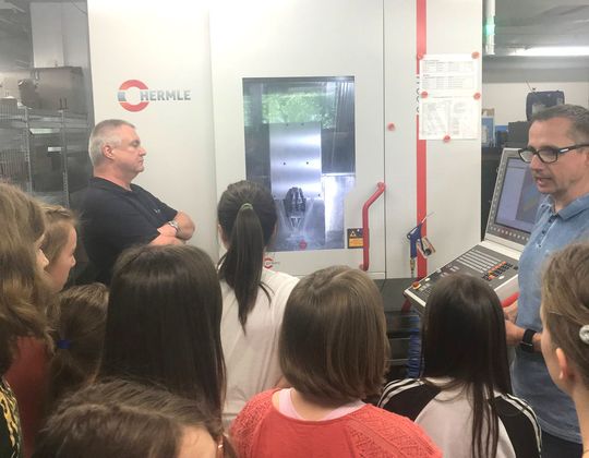 Die Mädchen beobachten die Produktion eines Werkstücks an einer der CNC-Fräsmaschinen, Thomas Müller (rechts im Bild) erklärt die Technik. Die Mädchen beobachten die Produktion eines Werkstücks an einer der CNC-Fräsmaschinen, Thomas Müller (rechts im Bild) erklärt die Technik.