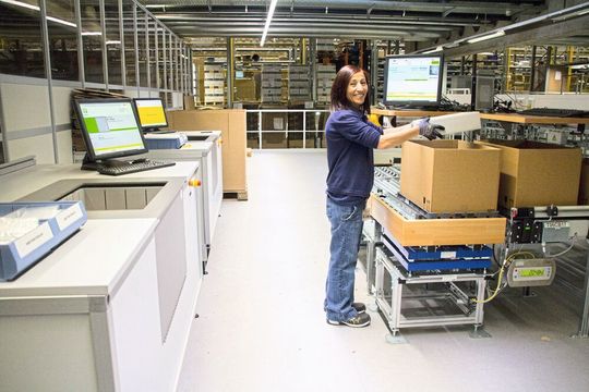 Unterschiedliche Artikel binnen kürzester Zeit bereitstellen: Dazu eignet sich die Kommissionierung nach dem Ware-zur-Person-Prinzip, bei dem die Artikel in Behältern direkt am Arbeitsplatz bereitgestellt werden.