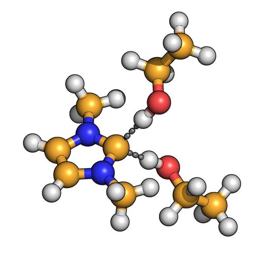 Das Kohlenstoff-Atom des Carbens (gelb) bildet gleichzeitig Wasserstoffbrücken (gestrichelt dargestellt) zu zwei Molekülen aus. Das Kohlenstoff-Atom des Carbens (gelb) bildet gleichzeitig Wasserstoffbrücken (gestrichelt dargestellt) zu zwei Molekülen aus.