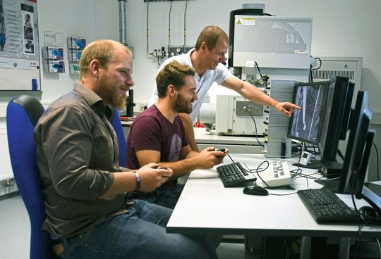 Forschung kann Spaß machen: Christian Dolle, Peter Schweizer und Prof. Dr. Erdmann Spiecker (von links nach rechts) beim anipulieren von Versetzungen an ihrer Nano-Werkbank, einem erweiterten Elektronenmikroskop.