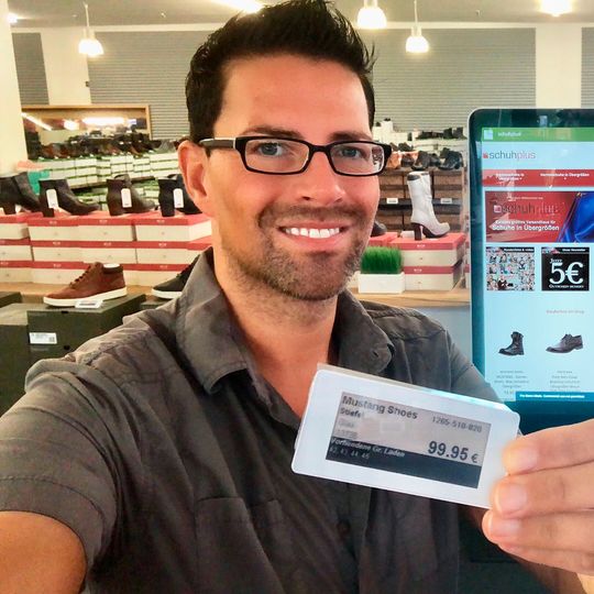Georg Mahn von Schuhplus präsentiert stolz ein digitales Display, im Hintergrund ist ein Touch-Stahdisplay im Fachgeschäft zu erkennen. Georg Mahn von Schuhplus präsentiert stolz ein digitales Display, im Hintergrund ist ein Touch-Stahdisplay im Fachgeschäft zu erkennen.