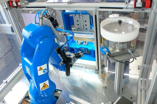 Gute Zusammenarbeit: Der Roboter legt u.a. Kleinteile in das Ventil ein …